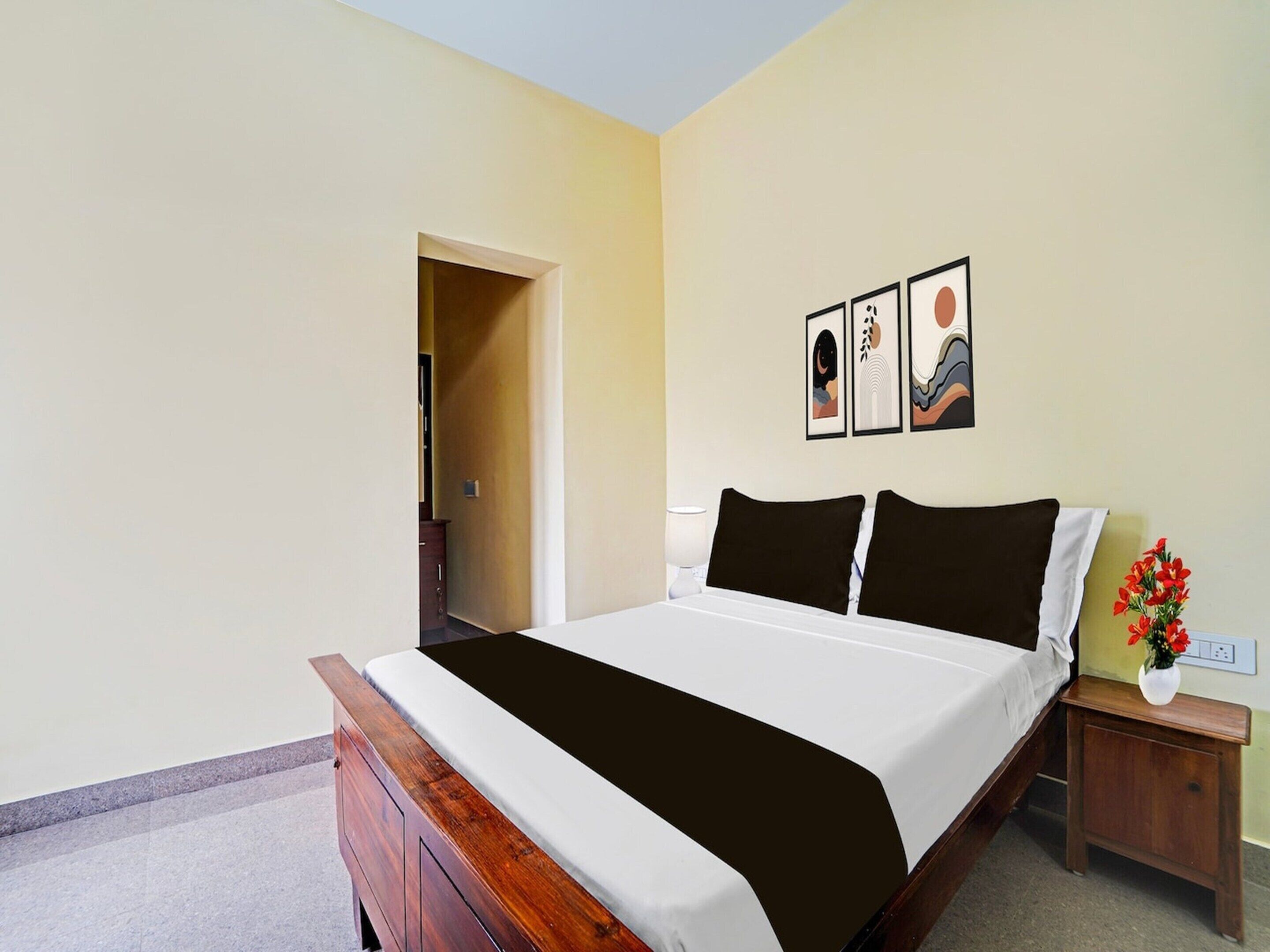 A bedroom with a wooden bed, a nightstand, a wall-mounted light, and a door leading to another room.