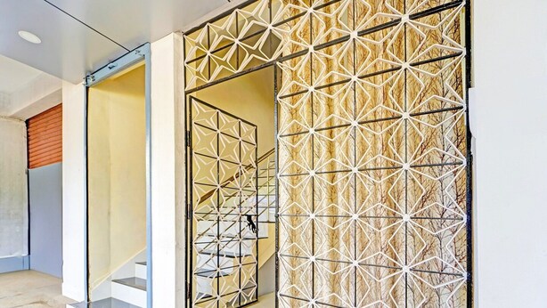 Ein modernes Interieur mit Wand in geometrischem Muster, einer Treppe und einer Glastür.
