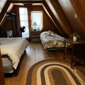 A cozy attic bedroom with a bed, a smaller bed, a fan, a lamp, and a plant. - Fall in the white mountains ! Aframe style ! (Conway)