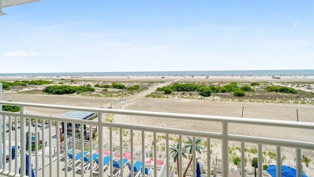 Uitzicht op het strand vanaf een balkon met lounge stoelen en een zwembad.
