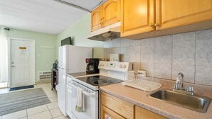 Een kleine keuken met een kookplaat, oven, magnetron en een spoelbak.