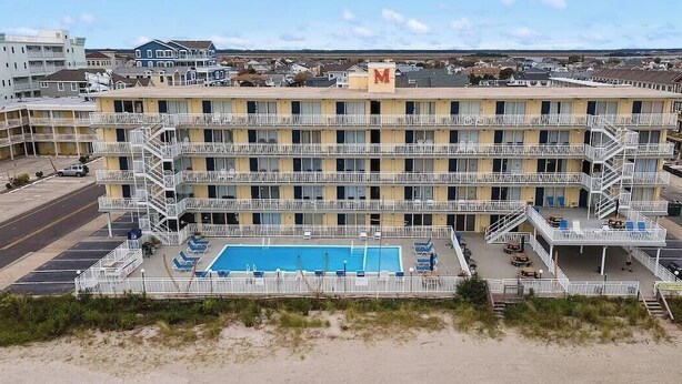 Un motel à plusieurs étages doté d’une piscine, d’un espace extérieur aménagé avec des sièges et d’un parking.