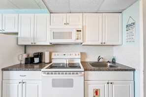 A kitchen with white cabinets, a microwave, a stove, and a sink. - 1 Bedroom Beach Condo with a Pool & Balcony (Wildwood Crest)
