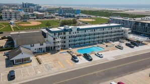 Un hotel con piscina, varios espacios de estacionamiento y un campo de béisbol al fondo.