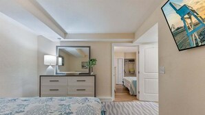 Un dormitorio con cama, cómoda, espejo y puerta que da a otra habitación.