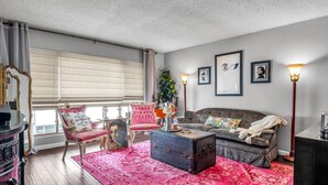 A living room with a large window, a sofa, a chair, a table, and a floor lamp.