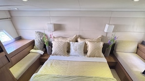 Un dormitorio moderno y bien equipado con una cama grande, varios almohadones, una mesita de noche y una pequeña planta en maceta.