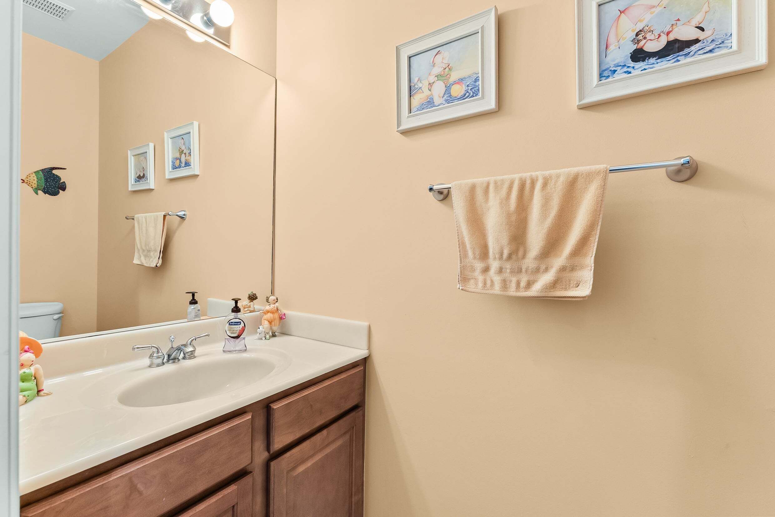 A bathroom with a sink, mirror, towel rack, and framed pictures on the wall.