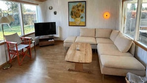 Una sala de estar con un sofá, una mesa de centro, un televisor y un cuadro en la pared.