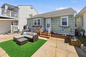 A residential property with a covered patio, outdoor seating, and a small garden area.