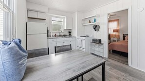 Une cuisine compacte avec des meubles blancs, une table à manger et un petit îlot central.