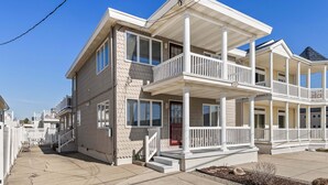 A two-story residential building with a balcony, a front porch, and a visible door. - 2BR Steps from Wildwood Beach with Private Outdoor Dining and Shower (Wildwood Crest)