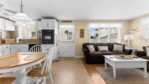 A modern kitchen with white cabinets, a dining table with chairs, a sofa, and a coffee table. - 2BR Steps from Wildwood Beach with Private Outdoor Dining and Shower (Wildwood Crest)