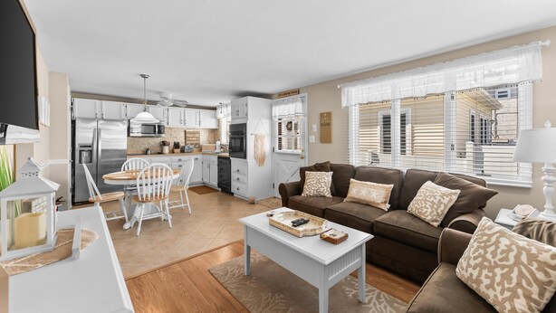 A modern living room with a sofa, coffee table, and dining area with chairs. - 2BR Steps from Wildwood Beach with Private Outdoor Dining and Shower (Wildwood Crest)
