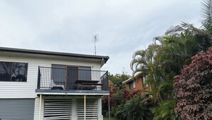 A two-story house with a balcony, a garage, and a well-maintained garden.