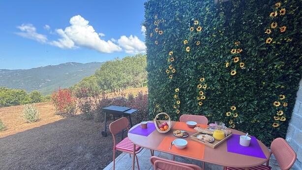 Una mesa lista al aire libre con sillas, una cesta y un mantel.