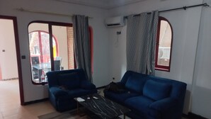Ein Wohnzimmer mit einem blauen Sofa, einem Couchtisch und einem gemusterten Teppich.