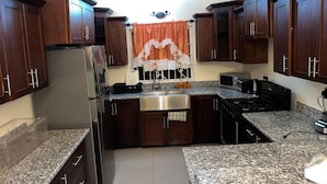 Una cucina con piani di lavoro in granito, elettrodomestici in acciaio inossidabile e pensili in legno scuro.