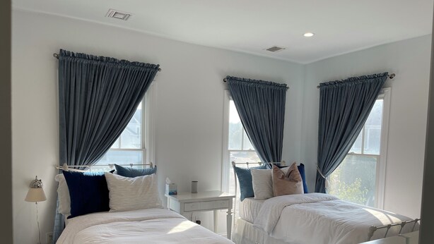 Una habitación de hotel con dos camas, una mesita de noche, una lámpara y una ventana con cortinas.