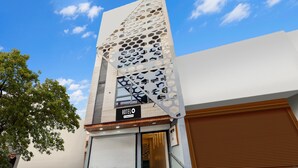 Ein modernes Hotel mit einer markanten, geometrischen Fassade, einem gut sichtbaren Eingang und einem Schild mit der Aufschrift 'HOTEL O'.