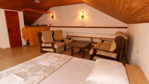 A bedroom with a bed, two armchairs, a small table, and a wooden ceiling. - Apartments Trojanović (Orebic)