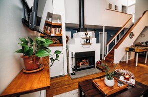 Ein modernes Wohnzimmer mit Kamin, Holzboden, einer Treppe und einem an der Wand befestigten Fernseher.