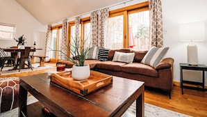 Una sala de estar acogedora con un sofá de cuero marrón, una mesa de centro de madera y un comedor con mesa y sillas.