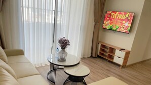 Una sala de estar moderna con un sofá, dos mesas redondas, un televisor y un mueble bajo.