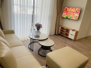 A modern living room with a sofa, two round tables, a television, and a small cabinet.