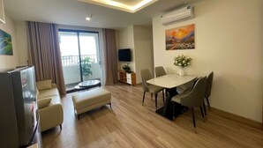 Una sala de estar moderna con comedor, televisor de pantalla plana y balcón con cortinas.