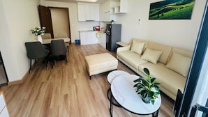 A modern living room with a sofa, a dining table, and a kitchen area in the background.