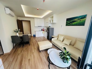 A modern living room with a sofa, a dining table, and a kitchen area in the background.