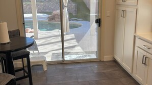 Une cuisine avec une porte-fenêtre coulissante donnant sur un patio avec une piscine.