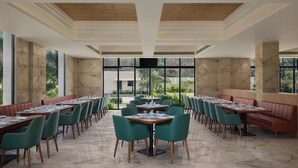 Un restaurante con paredes de mármol, sillas verdes y una mesa central.