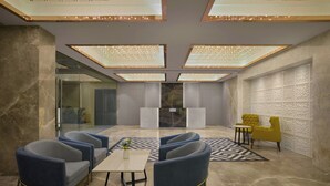 Un vestíbulo moderno con asientos, un mostrador de recepción e iluminación decorativa.
