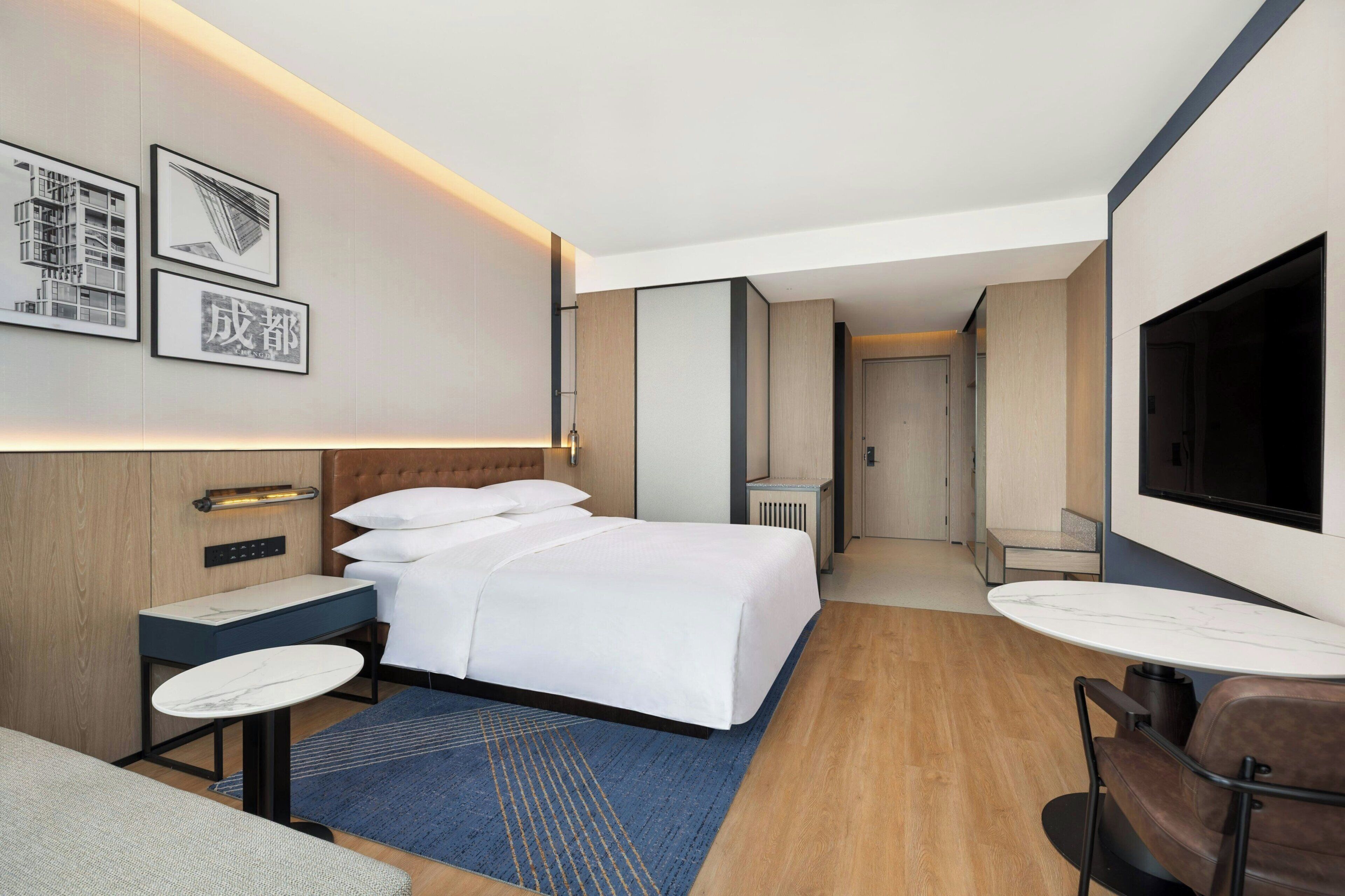 Une chambre d’hôtel moderne équipée d’un lit, de tables de chevet, d’un téléviseur et d’un coin salon.