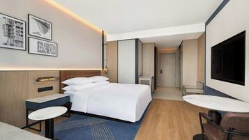 Une chambre d’hôtel moderne équipée d’un lit, de tables de chevet, d’un téléviseur et d’un coin salon.