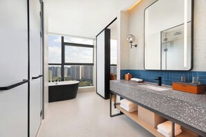 Un baño moderno con un ventanal grande, una bañera, un lavabo con encimera y un espejo.