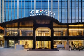 A modern hotel entrance with a prominent sign reading 'FOUR POINTS BY SHERATON.'