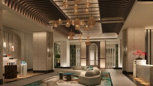A modern lobby with a reception desk, seating area, and decorative lighting.