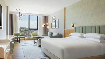 Camera d'albergo con un letto grande, una scrivania, una sedia, un divano e vista sulla città.