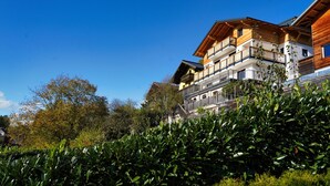 Un edificio de varios pisos con balcones, rodeado de vegetación.