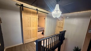 A staircase with a black railing, a wooden door, and a chandelier.