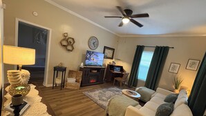 Una sala de estar con chimenea, televisor, ventilador de techo y sofá.