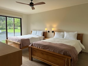 Ein Hotelzimmer mit zwei Betten, einem Deckenventilator und einem großen Fenster.