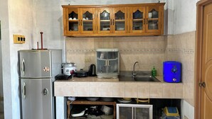 Una cocina compacta con refrigerador, estufa, pileta y muebles de madera.