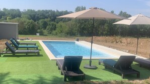 A swimming pool with lounge chairs and umbrellas, surrounded by greenery. - Charming estate with swimming pool - Group gîte for 15 people. (Castéra-Verduzan)