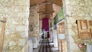 A stone corridor with wooden beams, a checkered floor, and a purple door at the end. - Charming estate with swimming pool - Group gîte for 15 people. (Castéra-Verduzan)