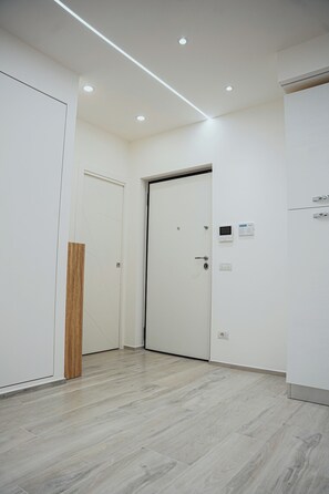 A hallway with a wooden accent wall, a white door, and a control panel on the wall. - LUXURY SEA EZLIN HOUSE (Savona)