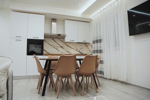 A modern kitchen with white cabinets, a marble countertop, and a dining area with four chairs. - LUXURY SEA EZLIN HOUSE (Savona)